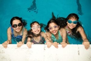 Four students wearing goggles and smiling in pool at Sir Edward residential English summer camp