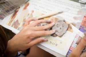 Student holds clay smiley face still as they continue crafting in clay modelling activity at Sir Michael English summer camp