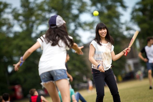 Student pitches to student with rounders bat during sports activity at Sir Michael English summer camp