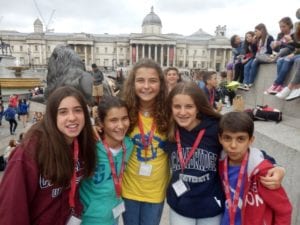 Five students smile at the camera in front of Trafalgar Square on excursion at Sir Edward residential English summer camp