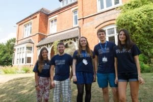 Welfare team at Sir Laurence residential English summer camp smile on lawns of Lucy Cavendish college