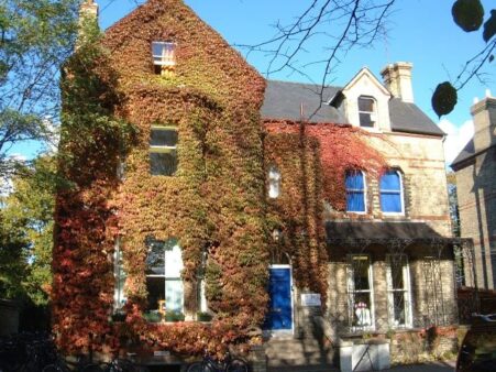 Studio Cambridge Main School in Autumn. There is a Virginia Creeper with red and yellow leaves climbing the school exterior